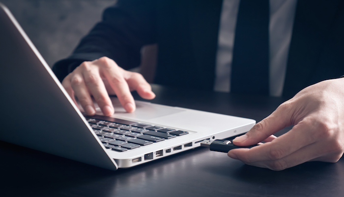 IT security audit. A man plugs a USB into a laptop