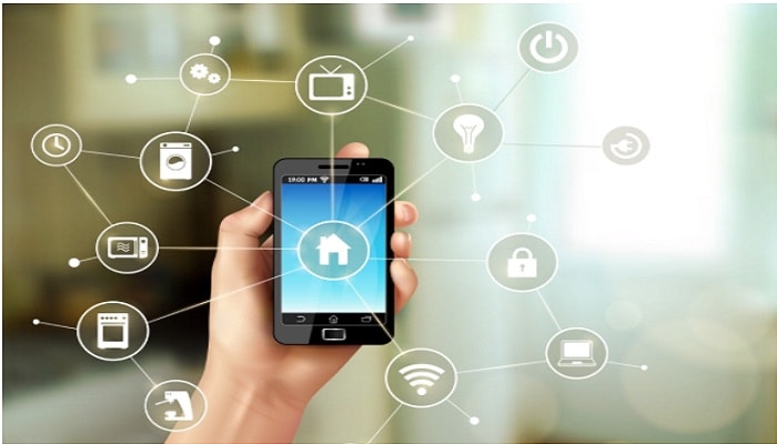 Home Automation. A user holds a phone controlling many IoT devices