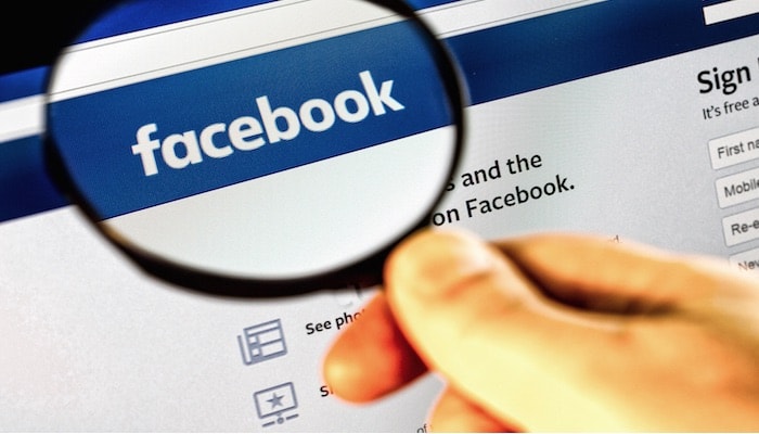 IT Security - Facebooks' homepage viewed with a magnifying glass focusing on the logo