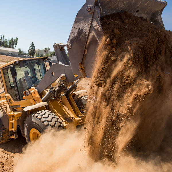 Managed IT Services for Civil Construction. A bulldozer tips a pile of dirt