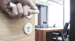 Return to Office. A hand opens an office door as the occupant returns to work